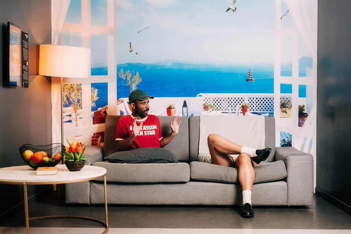 Paradox Museum Paris: Priority Entry Ticket Two people sitting on a gray couch in a room with a coastal-themed backdrop, a side table with flowers and fruit nearby.