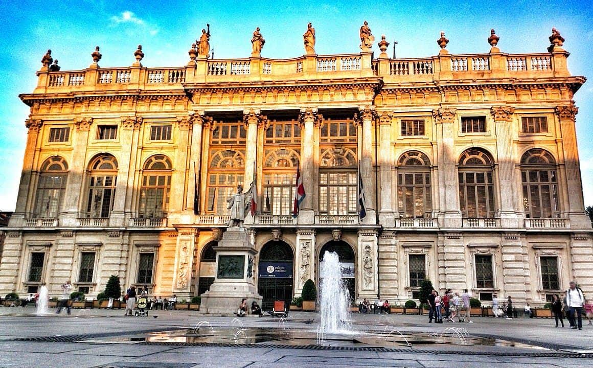 Palazzo Madama: Skip The Line Ticket A grand building with statues on the roof, large arched windows, and a fountain in front. Statues and flags are visible.