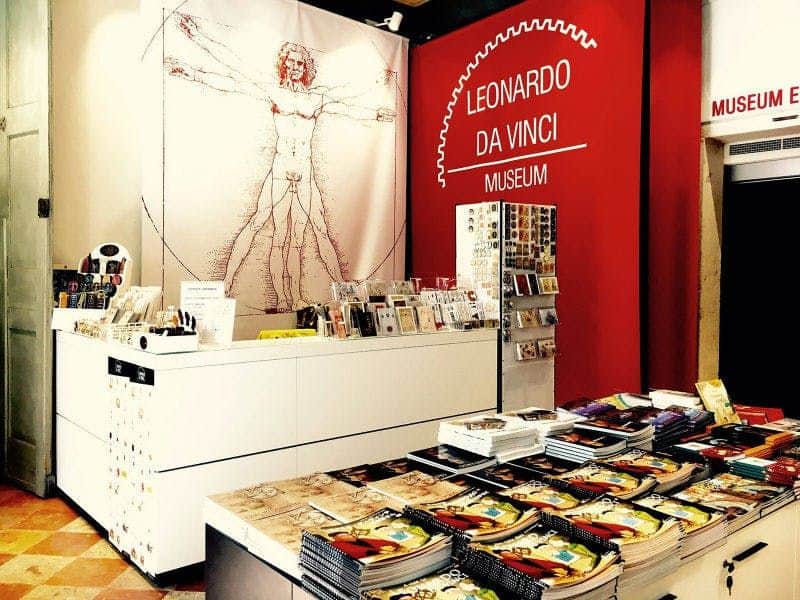 Leonardo da Vinci Museum Venice: Skip The Line Ticket Gift shop with Leonardo da Vinci-themed items, including books, postcards, and a Vitruvian Man poster. Sign reads "Leonardo da Vinci Museum."