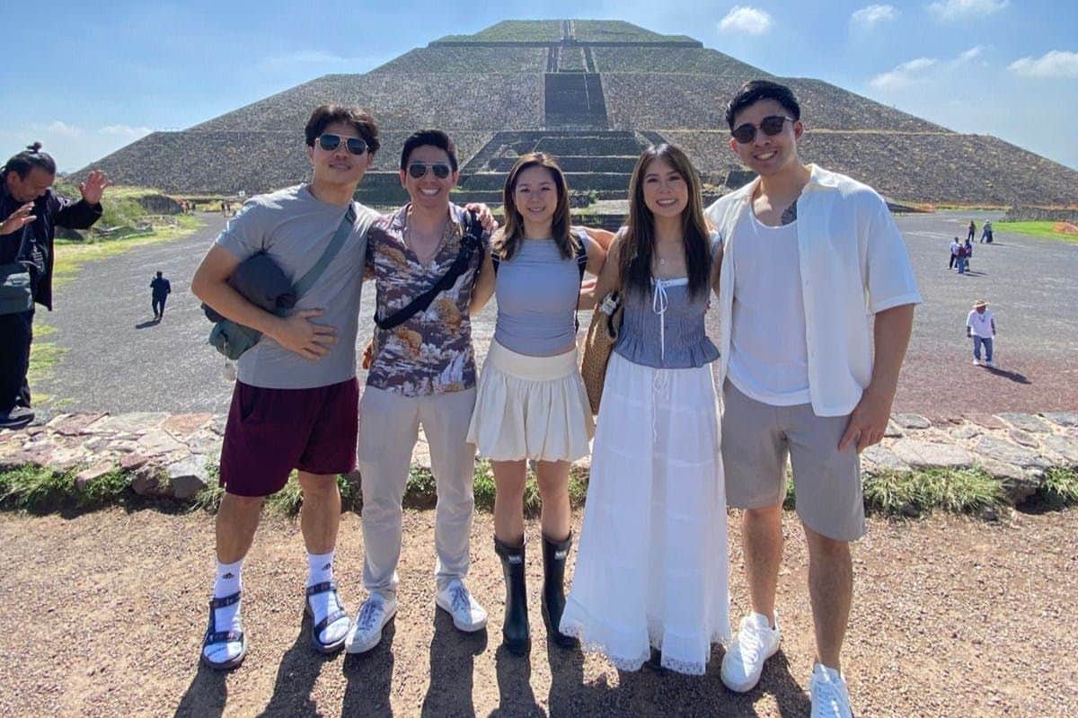 Teotihuacán Pyramids: Skip The Line Ticket + Guided Walking Tour Five people posing in front of a large pyramid on a sunny day. Everyone is smiling and wearing casual summer clothes.