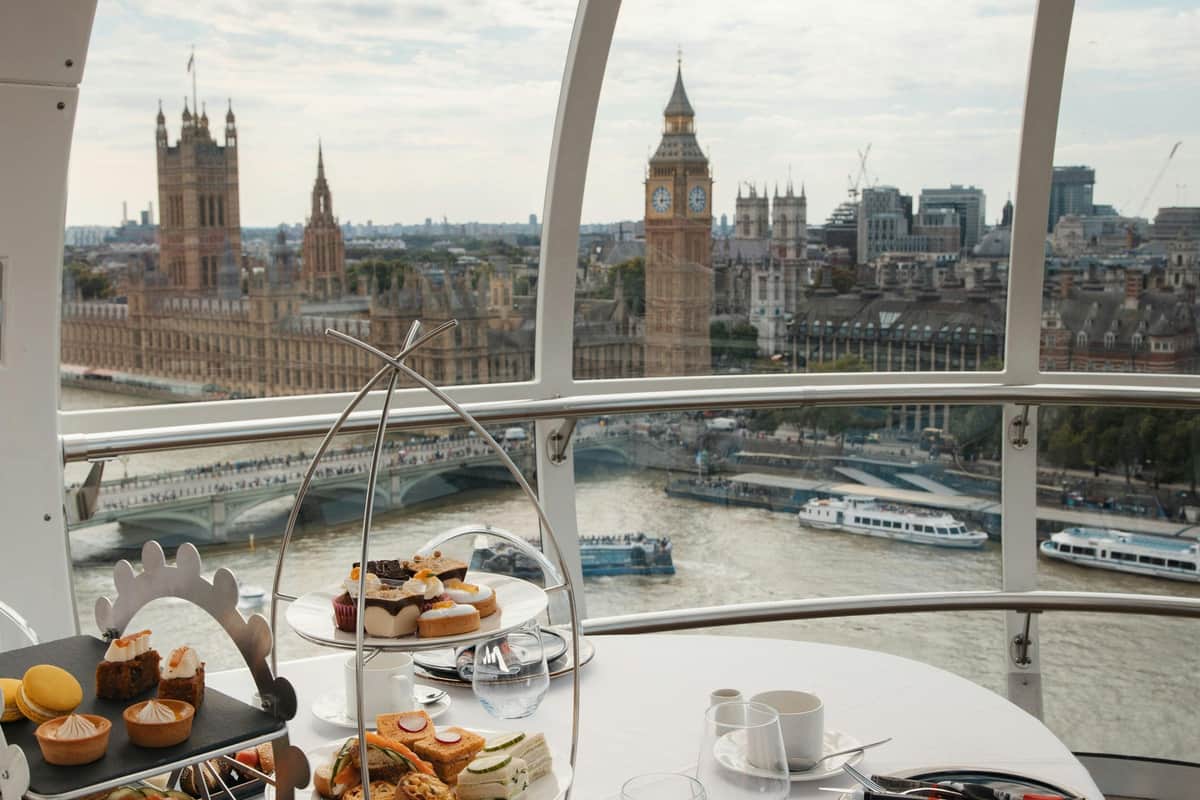 London Eye: Fast Track Ticket + Afternoon Tea Experience + Lounge Access Afternoon tea setup within the London Eye capsule overlooking Big Ben, the Thames River, and the Houses of Parliament.