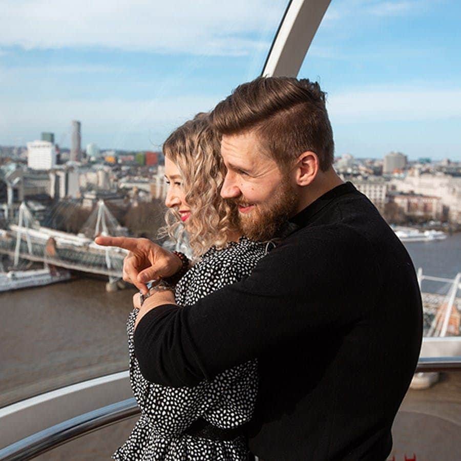 London Eye: Bilet szybkiego wstępu + Prywatny pod Para obejmuje się w kapsule diabelskiego młyna, z widokiem na rzekę i miejski pejzaż z mostami i budynkami w tle.