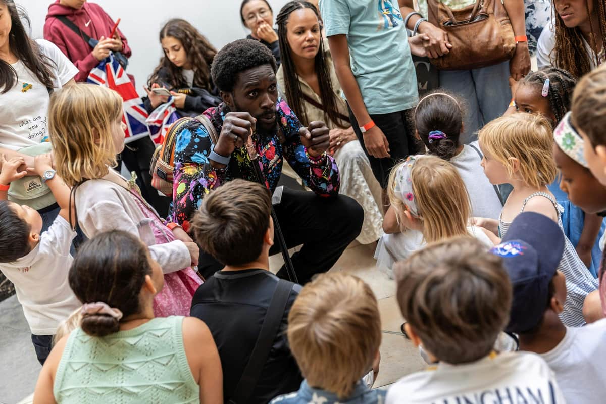 The National Gallery: Fast Track Ticket + Guided Tour for Children A man animatedly speaks to a group of children and adults gathered around him indoors.