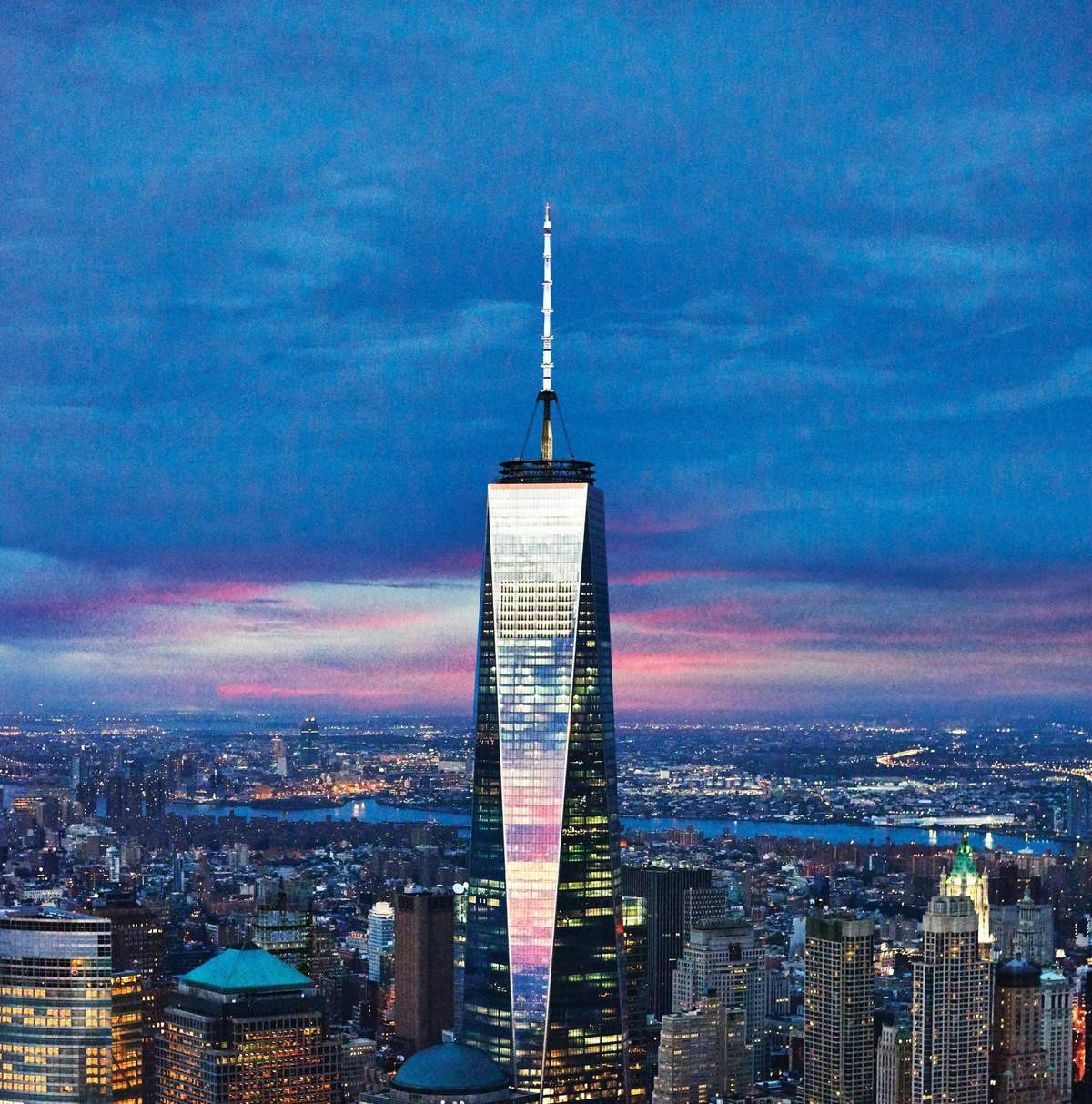 One World Observatory: Skip All Lines One World Trade Center towering above the New York City skyline at dusk, with a colorful sky in the background.