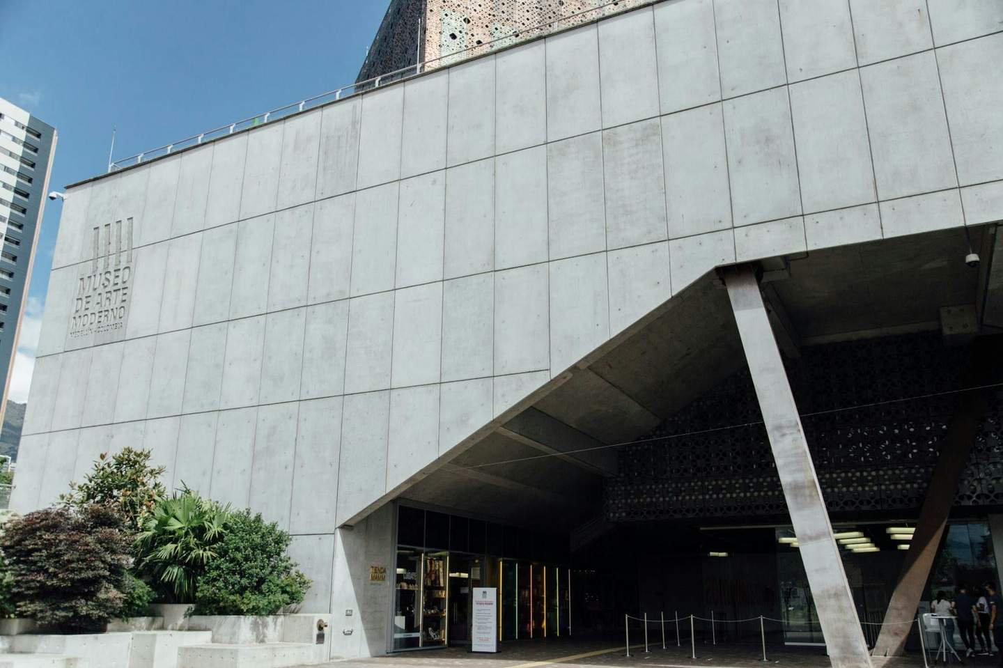 Modern gray concrete building with "Museo de Arte Moderno" sign, large entrance, and greenery in front.