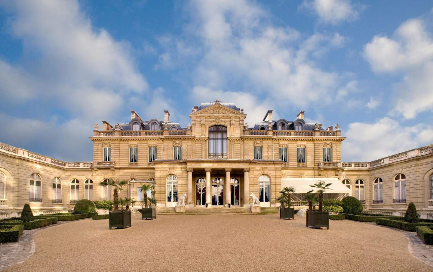 Musée Jacquemart-André Elegant stone mansion with large windows, arched doorways, and a central entrance adorned with columns, surrounded by a manicured courtyard.