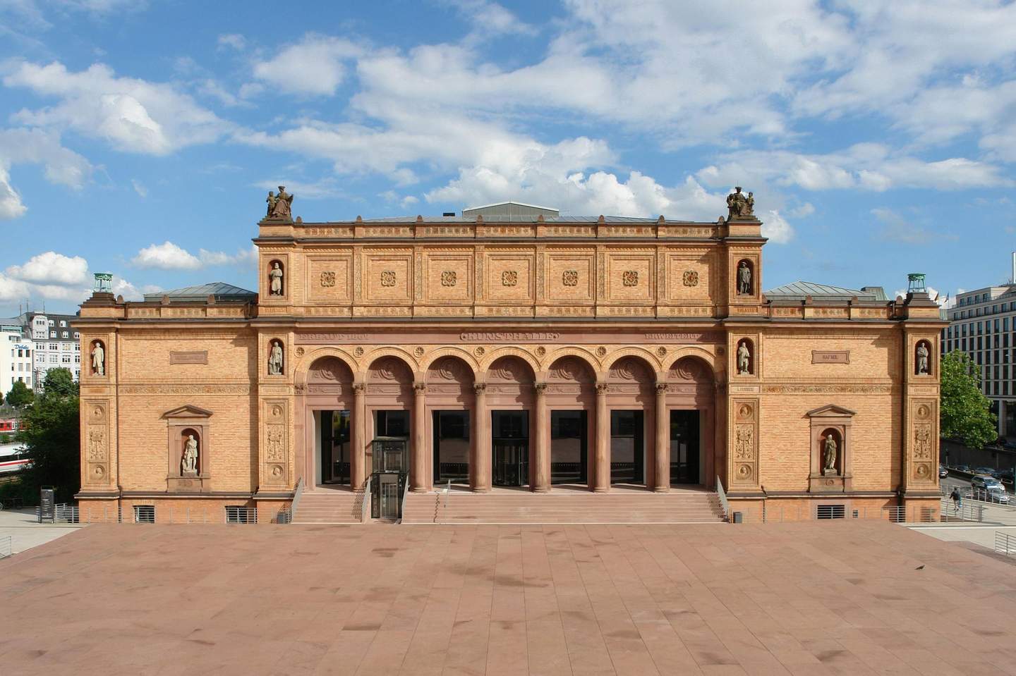 Hamburger Kunsthalle Historic building with an ornate façade, arched doorways, and statues in niches; stairs lead up to the entrance. Blue sky with clouds above.