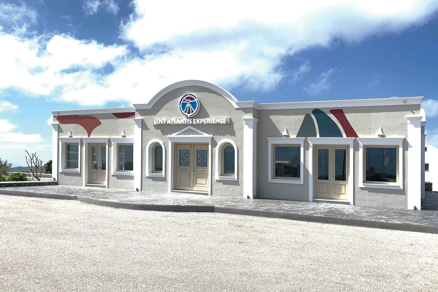 White building with colorful decorative shapes, labeled "Lost Atlantis Experience," under a blue sky with light clouds.