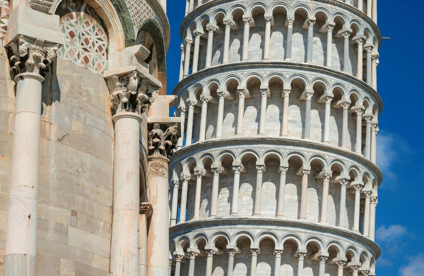 Leaning Tower of Pisa Close-up of detailed architectural columns and arches of leaning tower against clear blue sky.