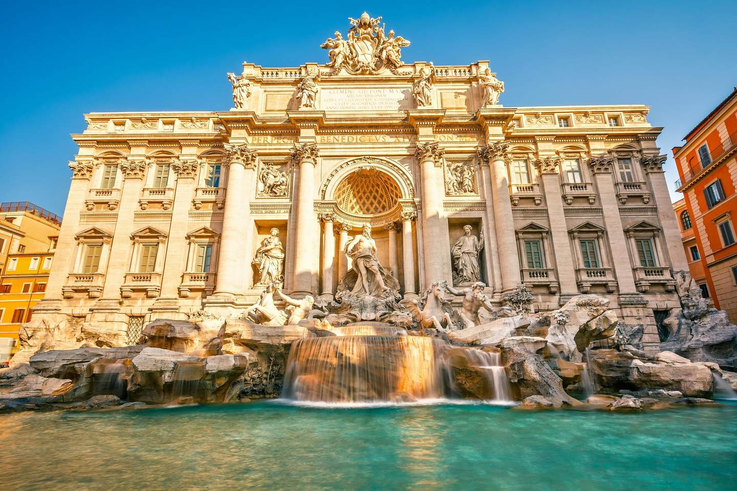 Trevi Fountain Baroque-style fountain with intricate sculptures and cascading water in front of a grand, ornate building under a clear blue sky.