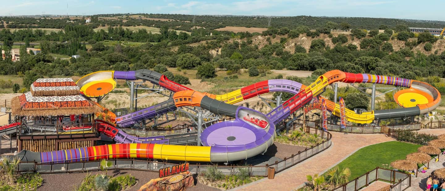 Aquopolis Villanueva A colorful water slide attraction with multiple intertwined paths, surrounded by greenery and a thatched-roof structure.