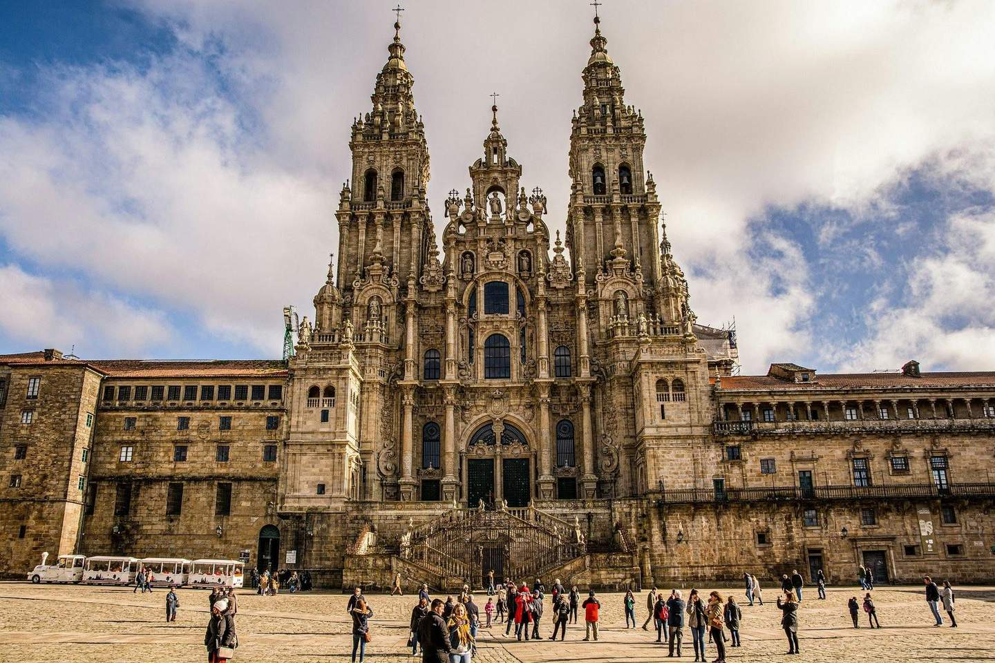 Cathedral of Santiago de Compostela A large, ornate cathedral with two towers and a central entrance, surrounded by people on a cobblestone plaza under a partly cloudy sky.