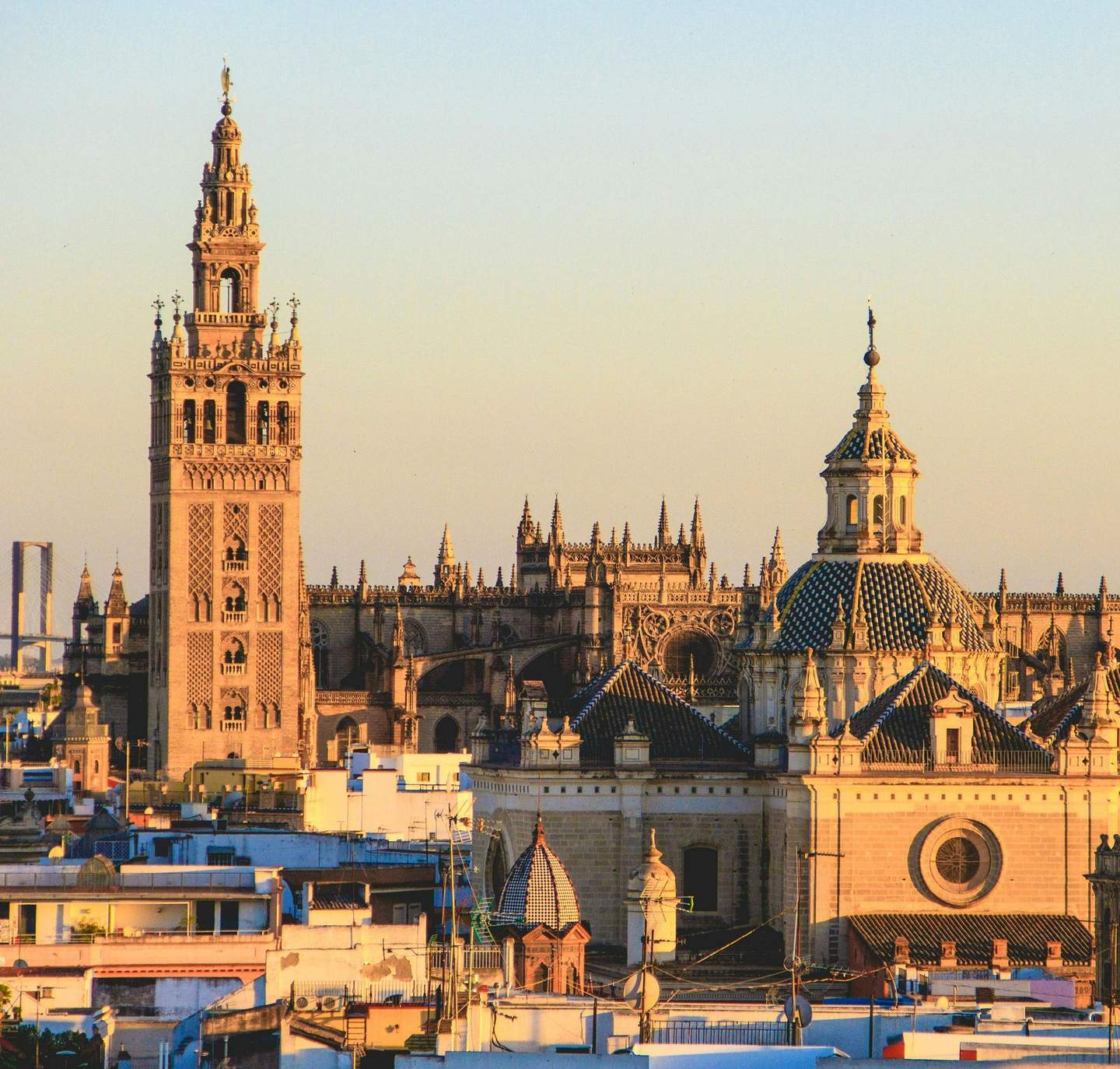 Seville Cathedral Historic cityscape featuring the Giralda tower and Seville Cathedral's dome at sunset, with rooftops in the foreground.
