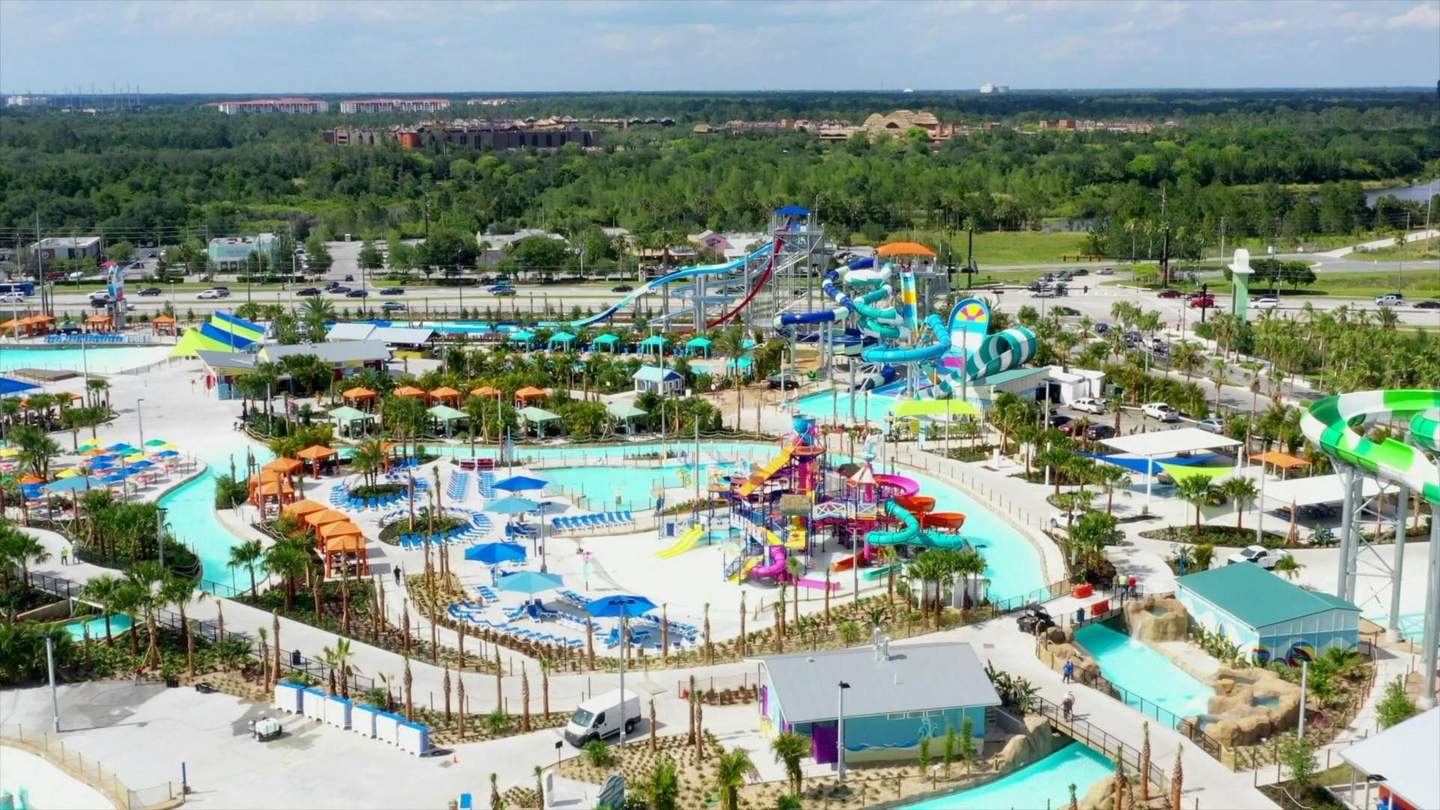 Island H2O Water Park Aerial view of a large water park with various colorful slides, pools, lounge chairs, and shaded areas under blue skies.