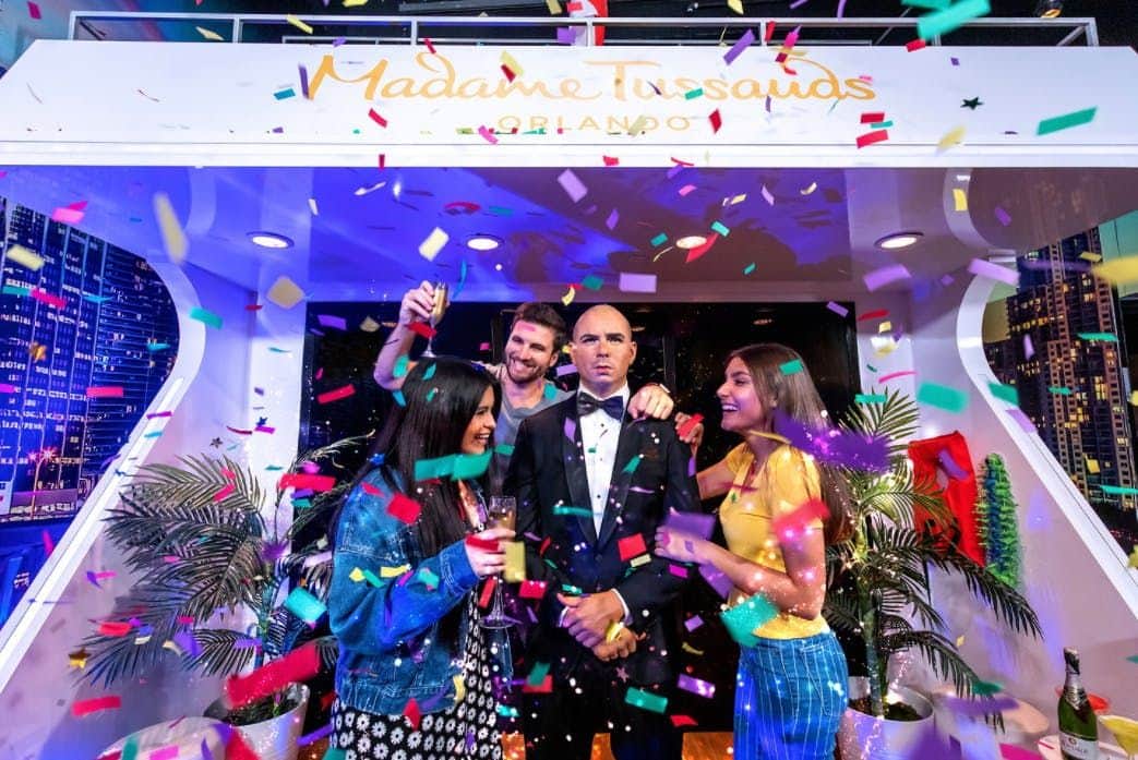 Madame Tussauds Orlando Three people celebrate with confetti and drinks around a wax figure in a tuxedo at Madame Tussauds Orlando.