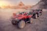 吉萨金字塔免排队门票+四轮摩托车或骆驼骑行+接送 Several red all-terrain vehicles parked on a desert landscape with pyramids and rocky surroundings in the background.